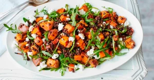 Lämmin bataattisalaatti, jossa on pinaattia, fetajuustoa ja hasselpähkinöitä